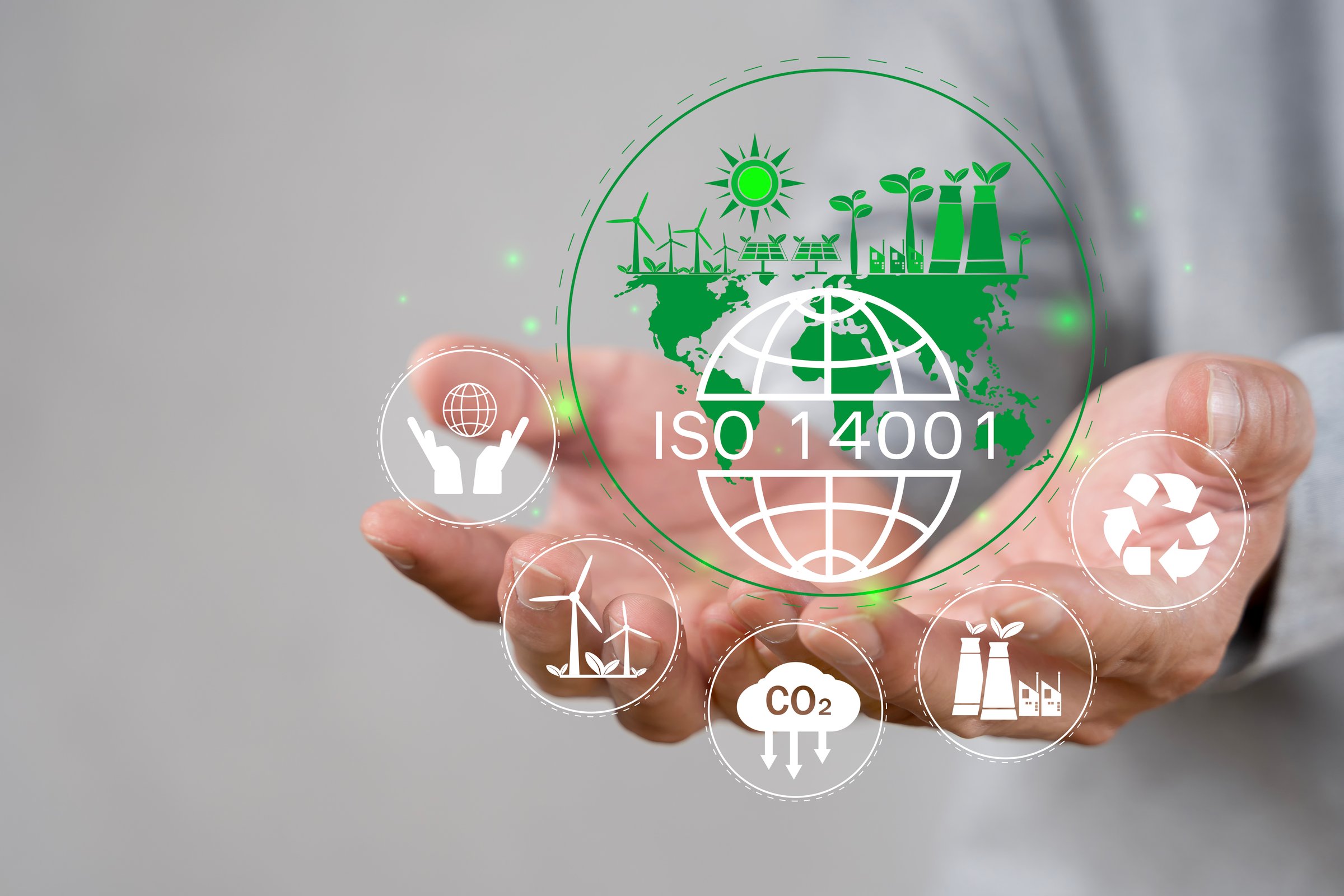 ISO 14001 concept. Businessman touch virtual icon of ISO 14001 certified for environmental management systems (EMS). Identify, control and reduce the environmental impact of activities.